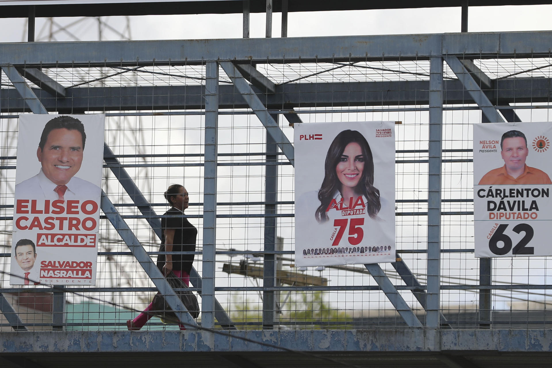 Una persona camina en un puente con carteles de campañas electorales este miércoles, en Tegucigalpa (Honduras). EFE/ Gustavo Amador