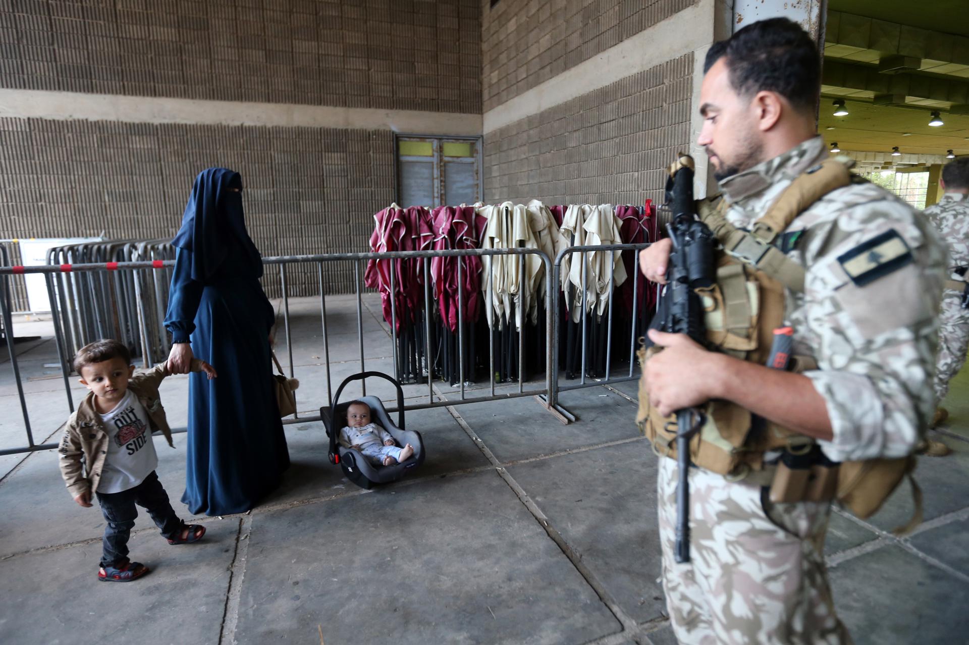 Una mujer refugiada siria espera con sus hijos mientras se preparan para partir hacia Siria, en Trípoli, norte de Líbano, 09 de octubre de 2025. Más de 160 personas están regresando de Trípoli a Idlib y Homs a través de un proceso organizado por ACNUR en coordinación con la OIM y la Seguridad General Libanesa. (Líbano, Siria) EFE/EPA/WAEL HAMZEH