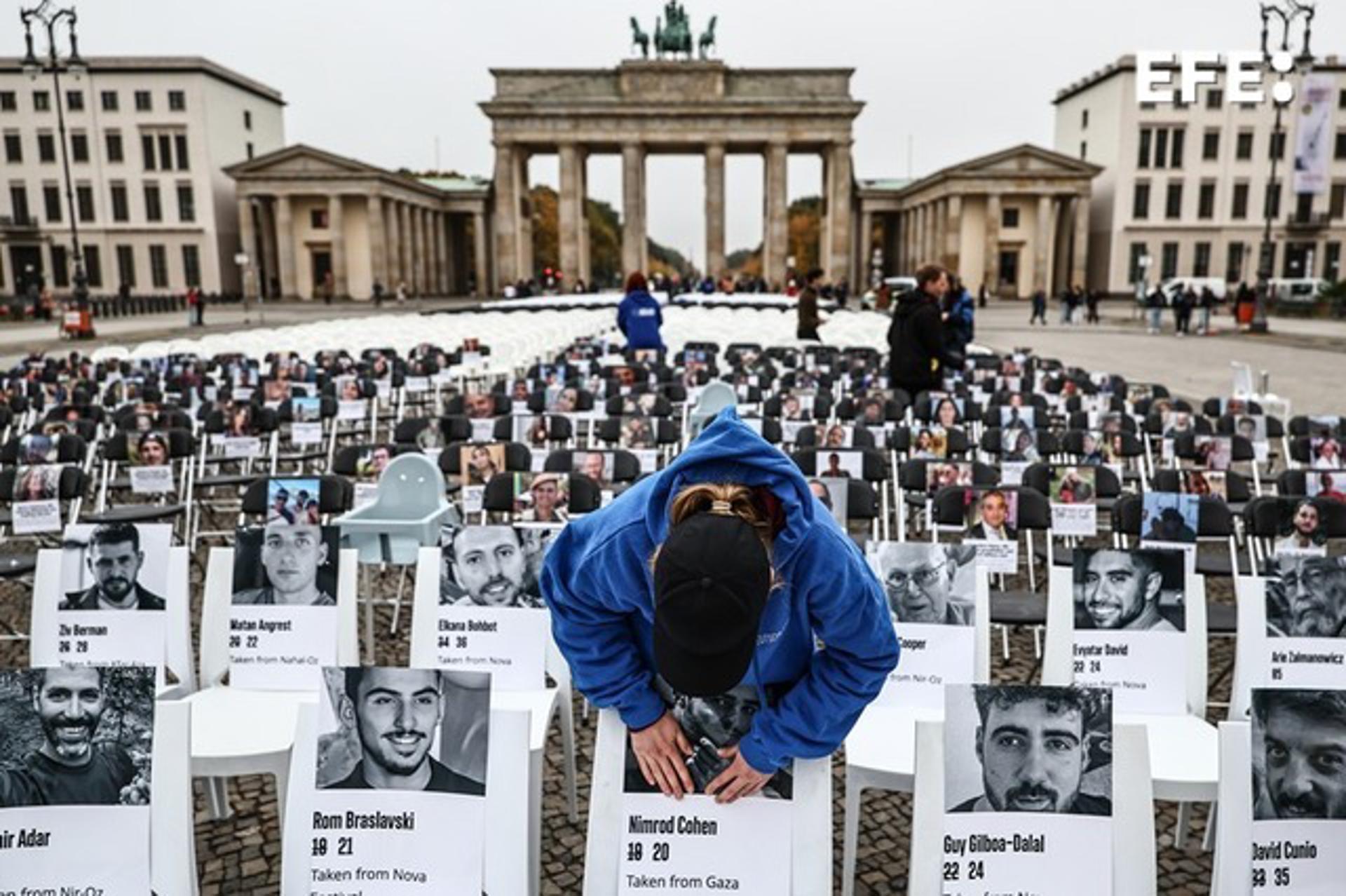 Una persona pega una foto en una silla durante una vigilia conmemorativa que marca el segundo aniversario del ataque de Hamas contra Israel, frente a la Puerta de Brandeburgo en Berlín, Alemania, el 07 de octubre de 2025. Más de 1,000 sillas con fotografías de víctimas y rehenes israelíes adjuntas a ellas se instalan en un memorial organizado por la Unión de Estudiantes Judíos de Alemania para recordar a las víctimas del ataque de Hamas. El 07 de octubre marca dos años desde que el grupo militante palestino Hamas lanzó un ataque sorpresa contra Israel, tomando decenas de rehenes y matando a casi 1,200 personas. En respuesta, Israel comenzó su guerra en Gaza, que ha matado a más de 66,000 personas, desplazado a millones y devastado el enclave palestino. (Protestas, Alemania) EFE/EPA/FILIP SINGER