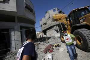 Trabajadores de la Cruz Roja caminan entre edificios destruidos en la ciudad de Gaza en una imagen de archivo. EFE/Mohammed Saber