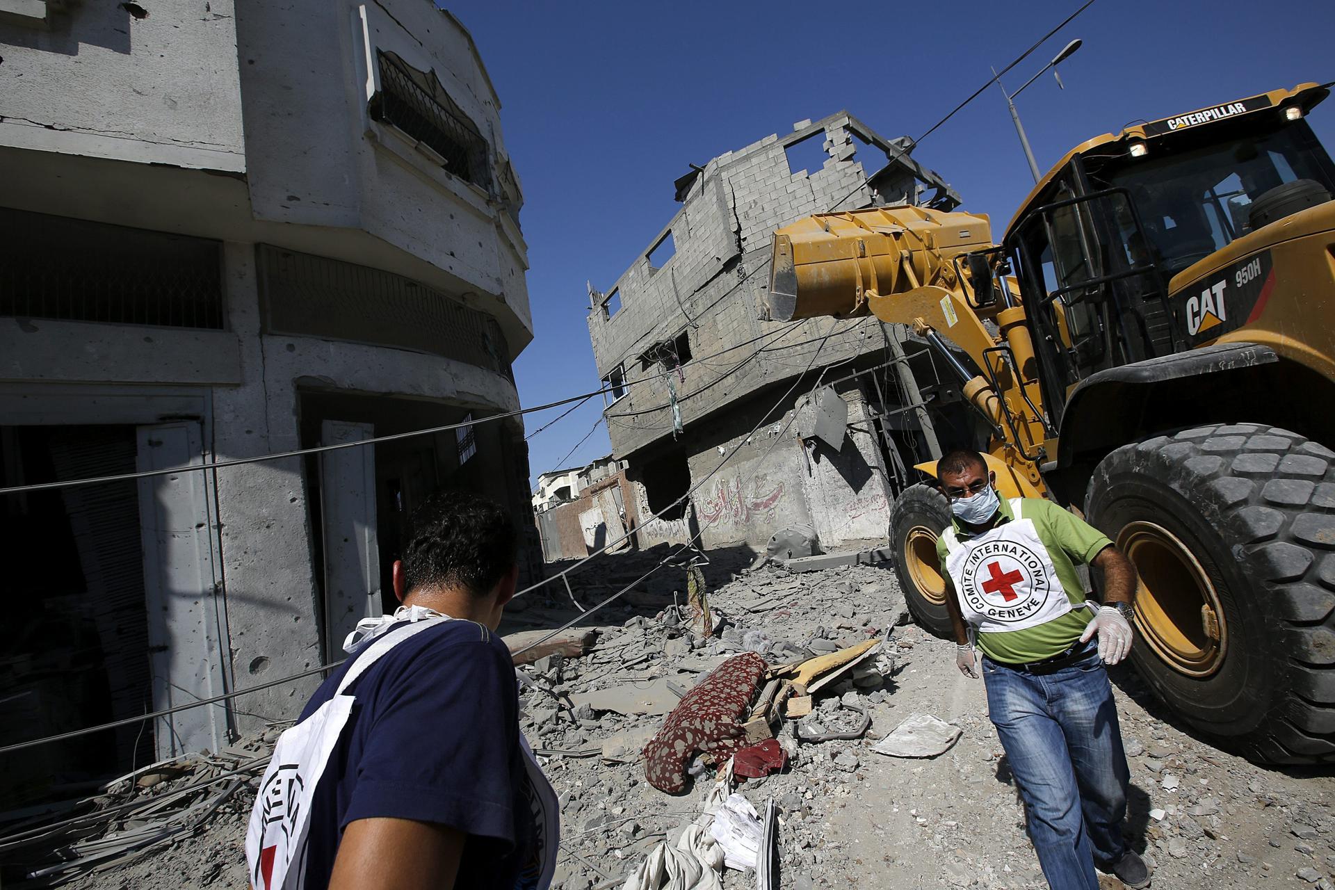 Trabajadores de la Cruz Roja caminan entre edificios destruidos en la ciudad de Gaza en una imagen de archivo. EFE/Mohammed Saber