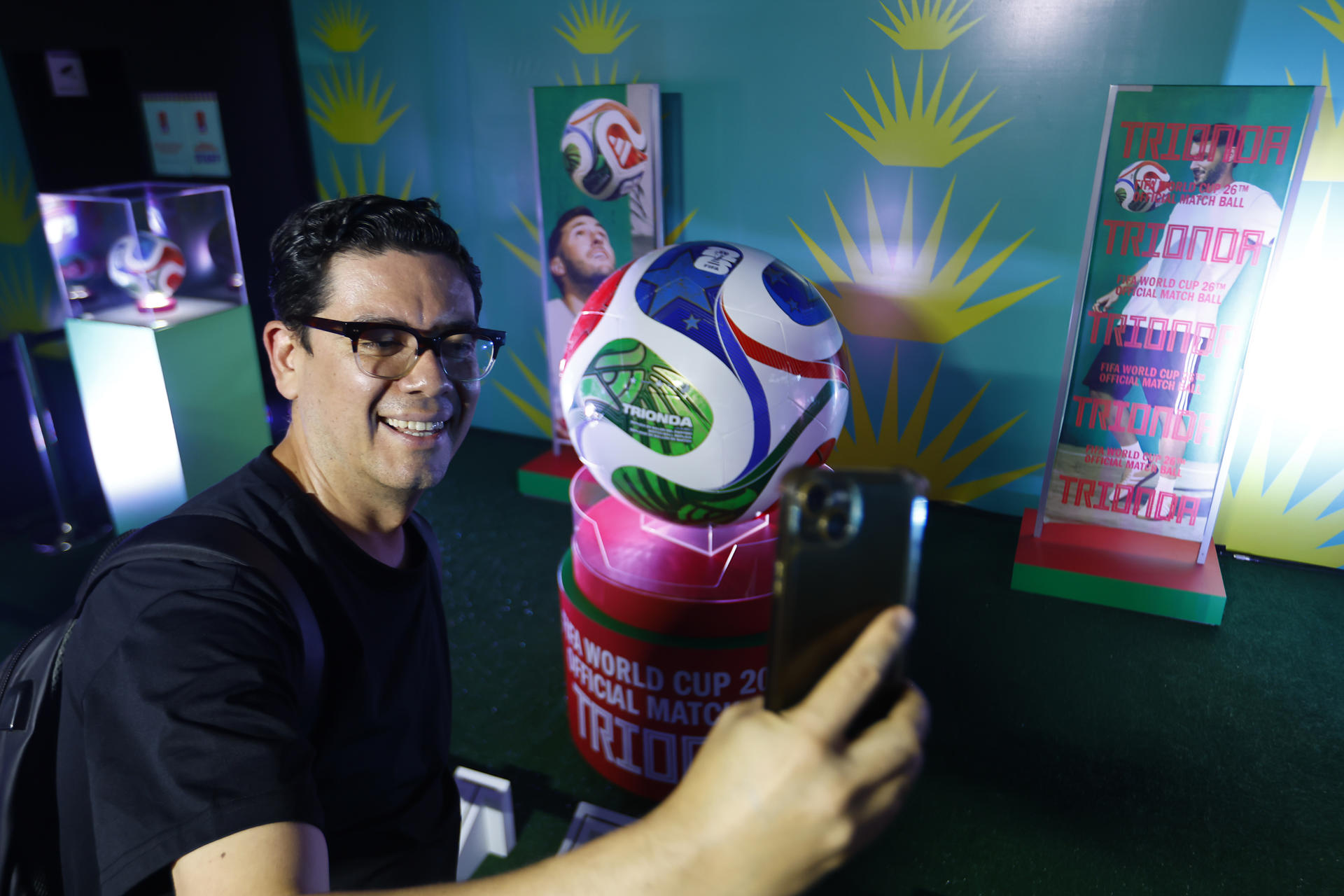 Un hombre se toma una fotografía junto al balón oficial de la Copa Mundial 2026 ‘Trionda’, durante la inauguración del pabellón 'El Alma del Mundial' este viernes, en Guadalajara (México). EFE/ Francisco Guasco
